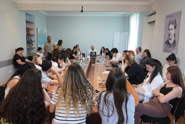 The exchange participants are sitting together round a big table. 